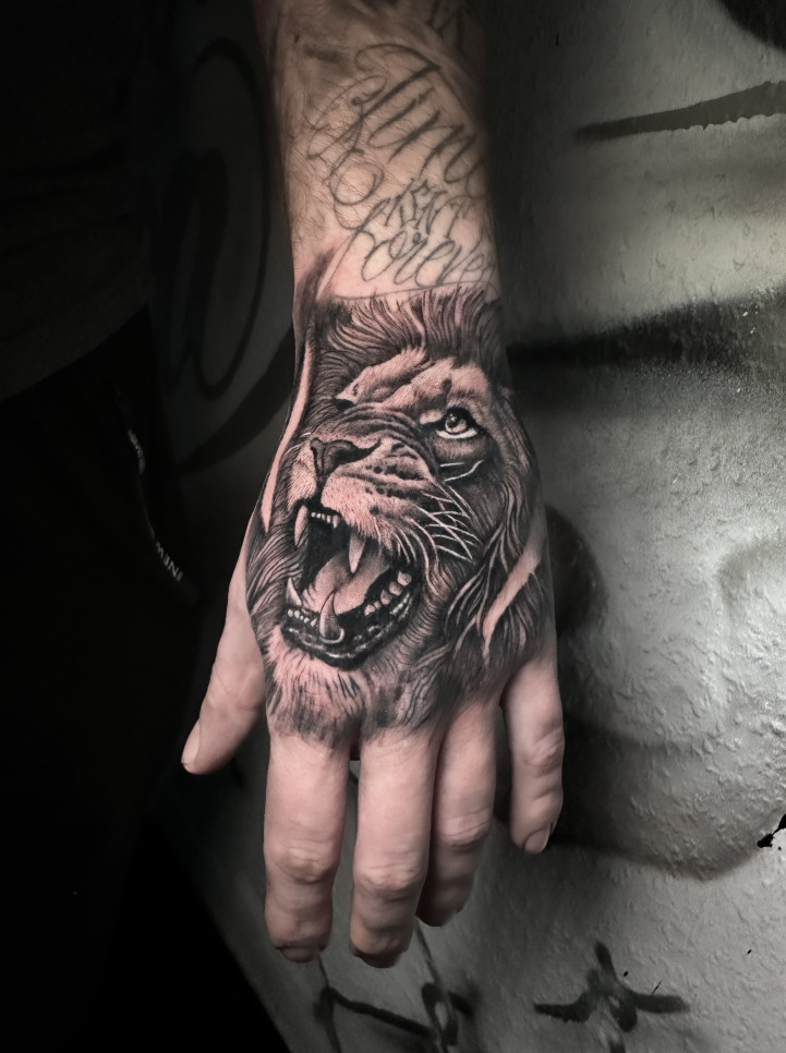 Realistic tattoo of a roaring lion on the hand